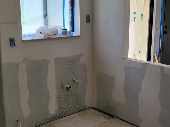 Bathroom under renovation with drywall, window, and plumbing