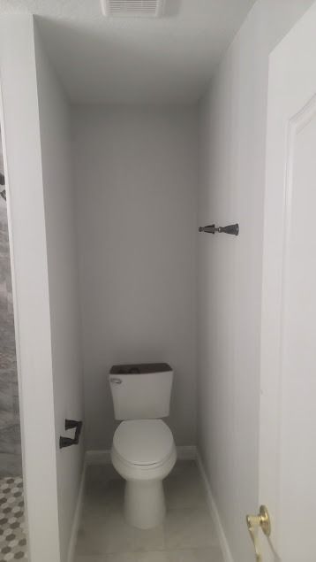 A small bathroom with a toilet, towel rack, and door