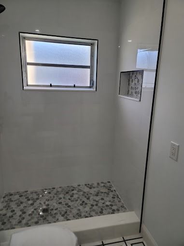 White shower with window, built-in shelf, and patterned floor