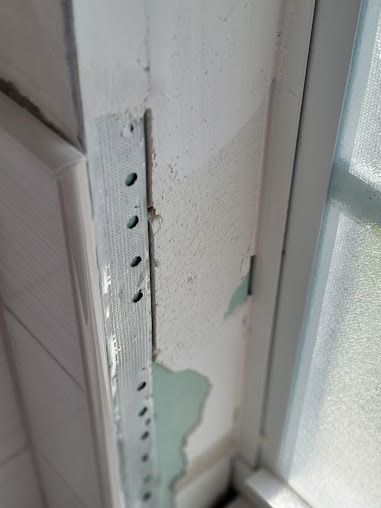 Close-up of a wall with peeling paint next to a window frame
