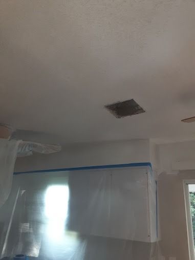 Ceiling with square vent, and a room with plastic sheeting and taped blue lines