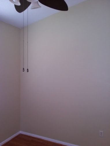 Empty beige room with a ceiling fan, hardwood floors, and light switches