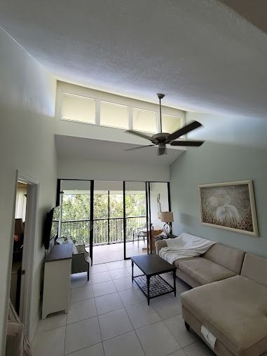 Living room with high ceiling, balcony, and neutral furniture
