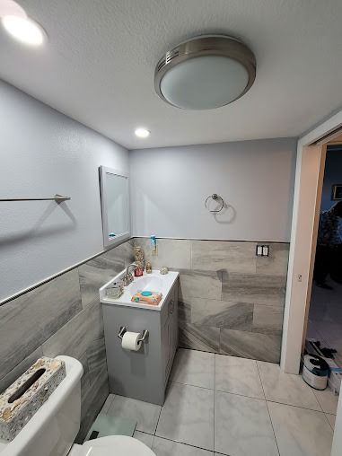 Small bathroom with gray walls, a toilet, sink, and light fixture