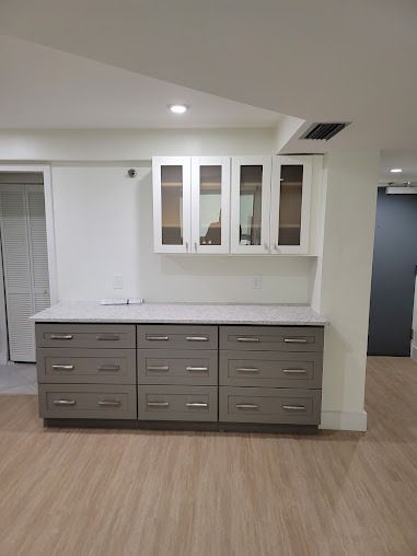 Gray and white cabinets with a marble countertop against a light-colored wall