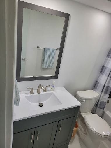 Bathroom with gray vanity, mirror, towel, and toilet
