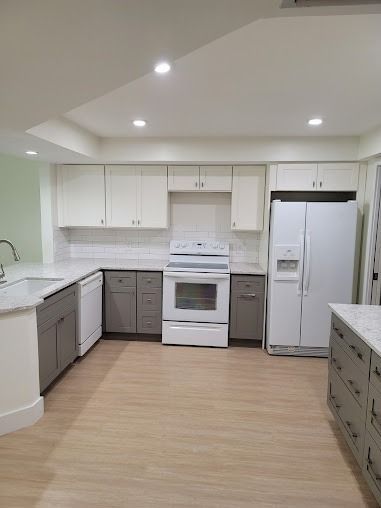 Modern kitchen with white and gray cabinets, white appliances, and light wood flooring
