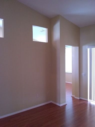 Interior view of a room with tan walls, square windows, and hardwood floors