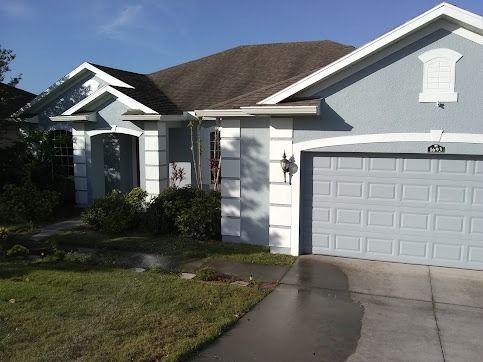 Blue house with white trim, garage door, and front door; sunny day