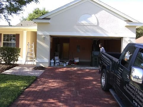 House exterior being painted; open garage; brick driveway