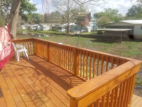 Wooden deck with railings, overlooking a pond, a white chair sits on the deck