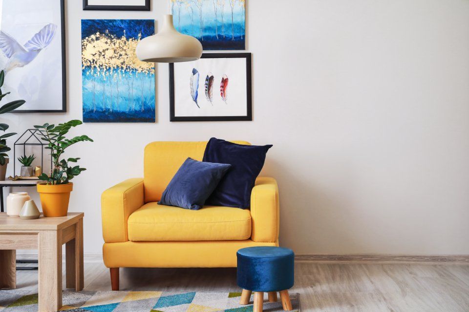 quadri colorati, poltrona gialla e cuscini blu