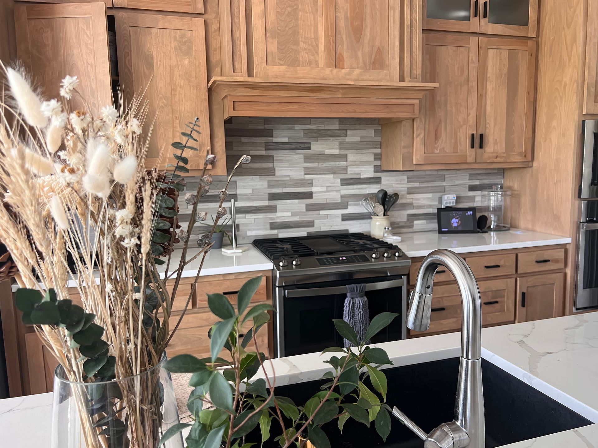 Wooden kitchen with black stove, tiled backsplash, and flowers on a white island counter