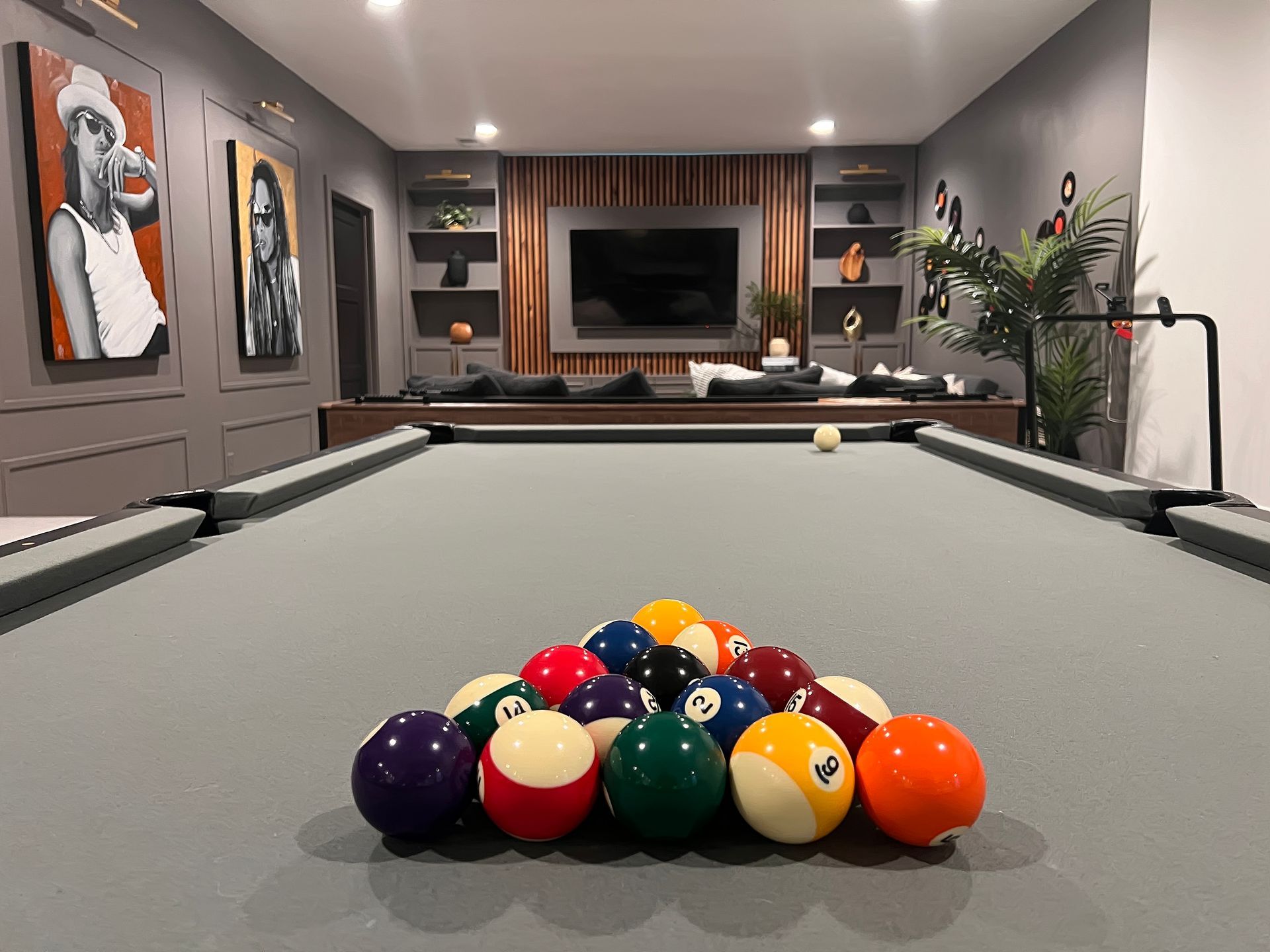 Pool table with a racked set of colorful billiard balls in a modern game room.