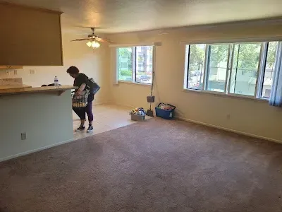 Woman in living room near a counter, boxes on the floor, windows in background.