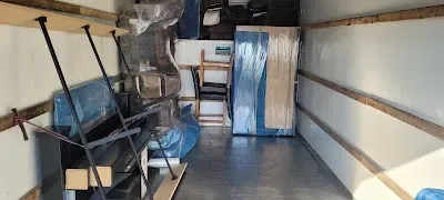 Inside a moving truck filled with wrapped furniture and boxes.