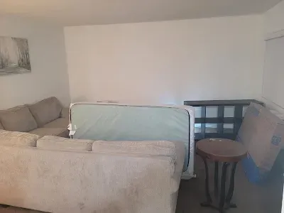 Living room with sectional sofa, mattress, end table, and sideboard.