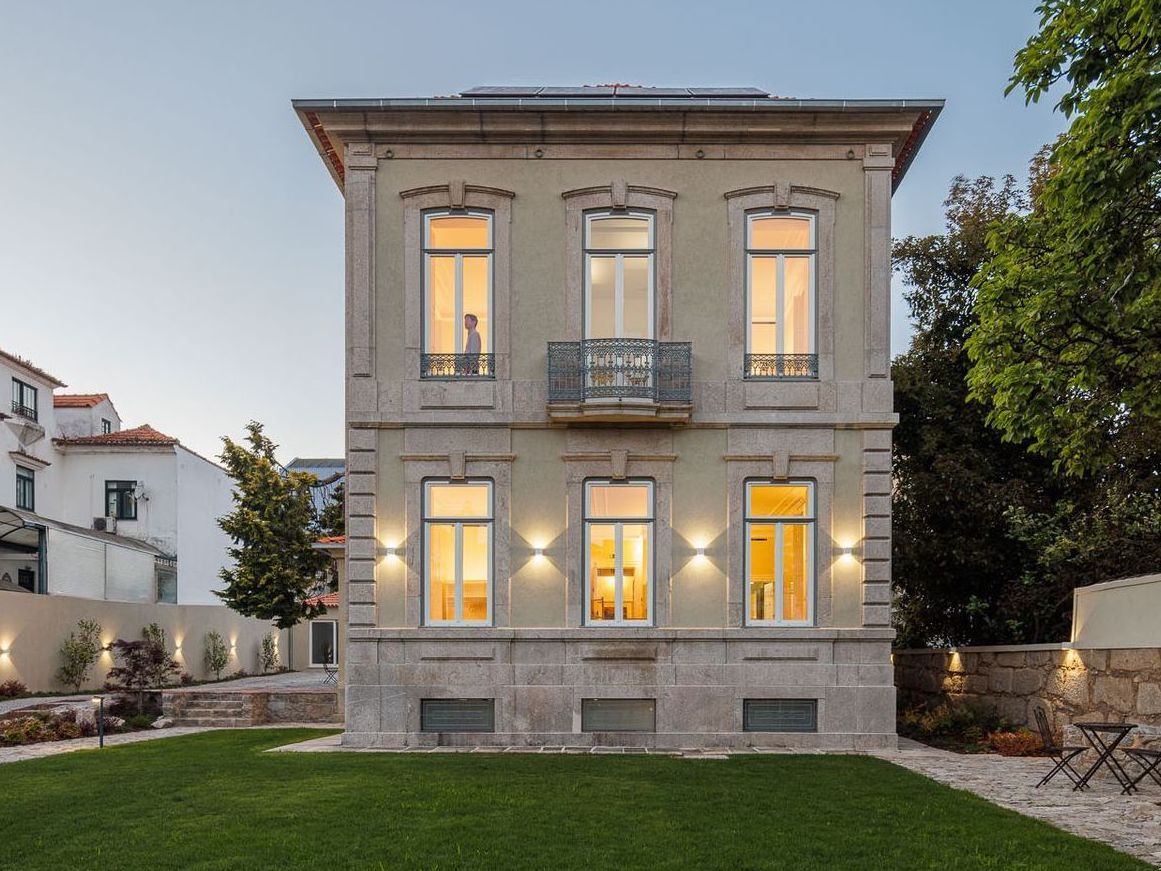 Casa Kala, restored by architect Ren Ito, with lit windows and garden at sunset