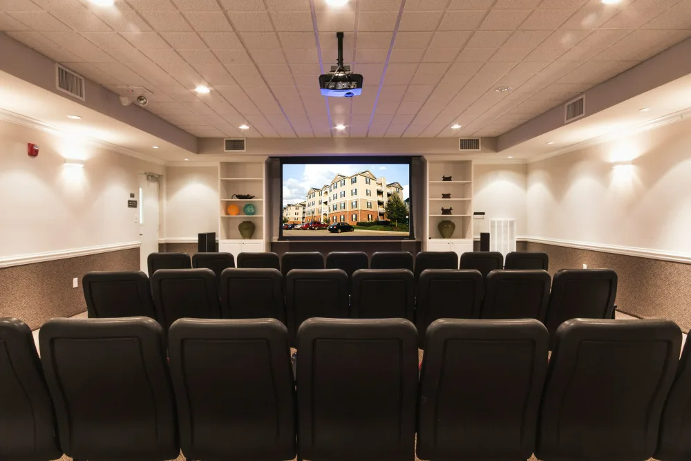 A movie theater with a projector and a large screen.