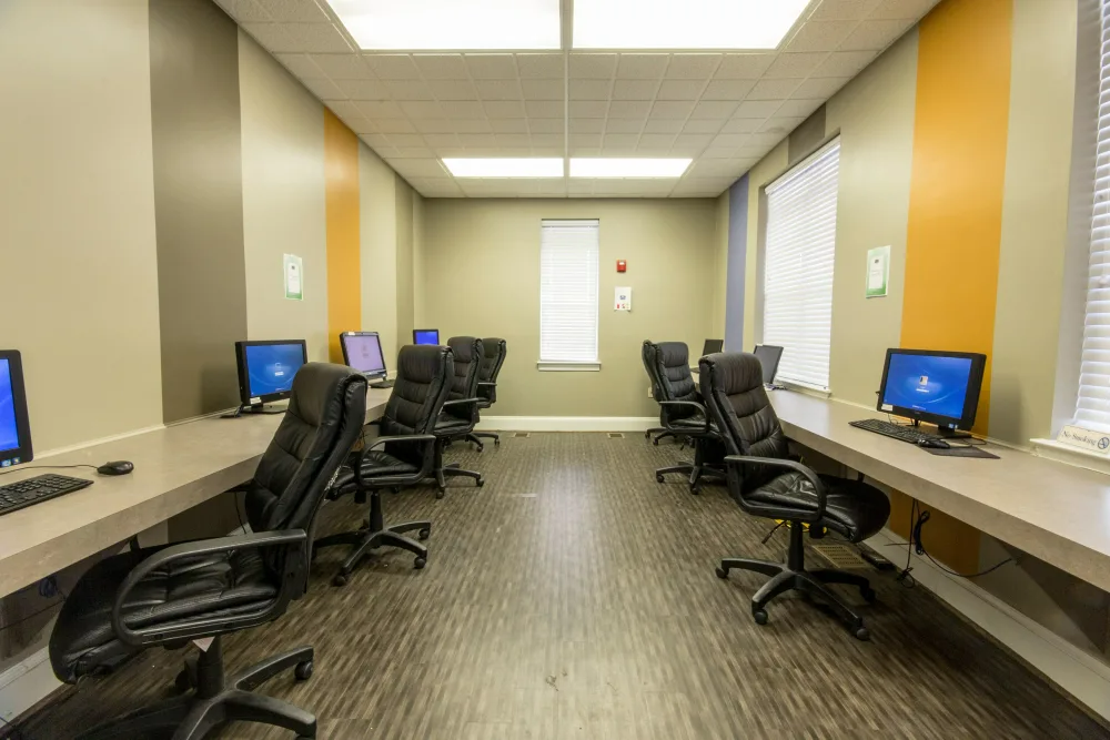 A room with a lot of computers and chairs in it