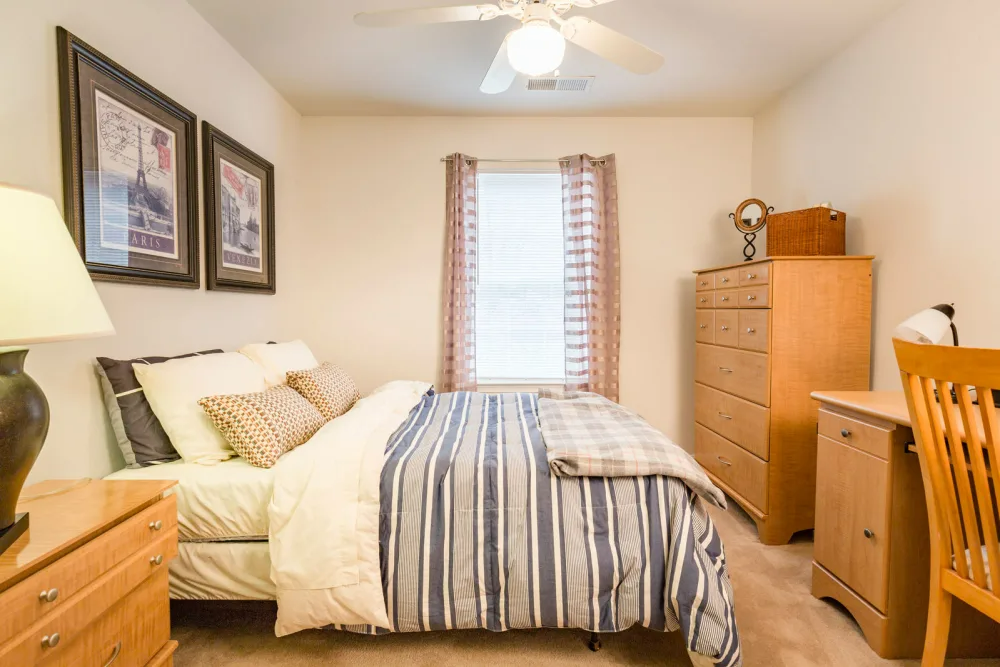 A bedroom with a bed, dresser, desk, and chair.