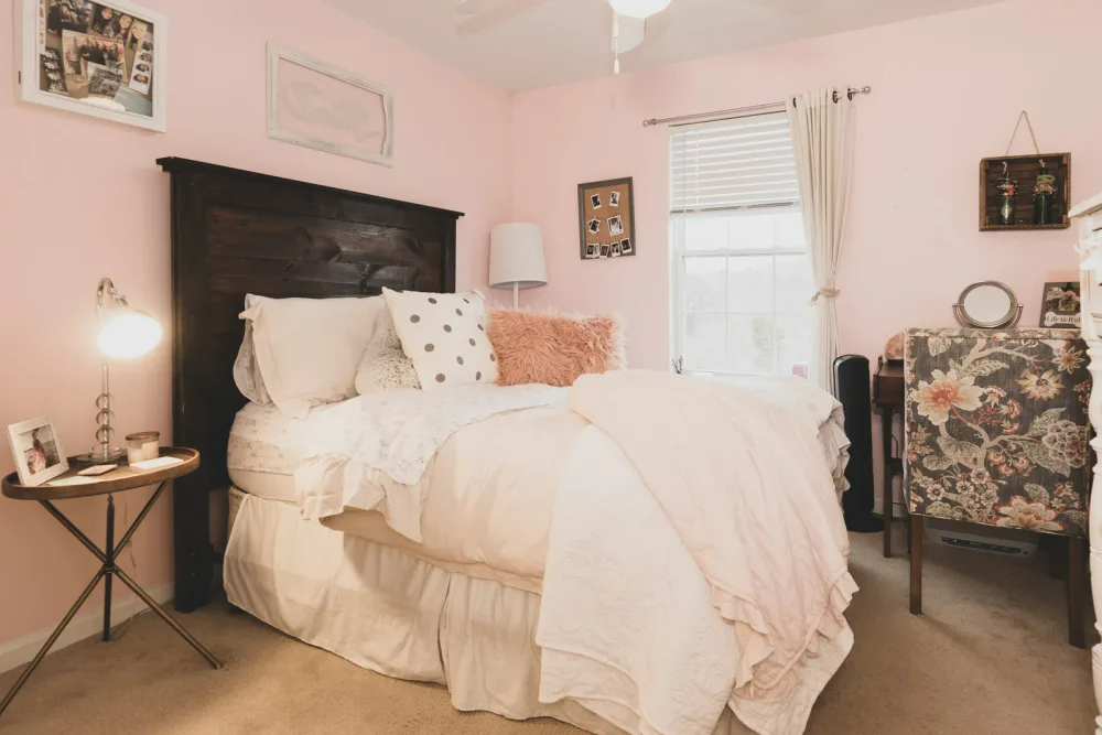 A bedroom with a bed, nightstand, desk, and chair.