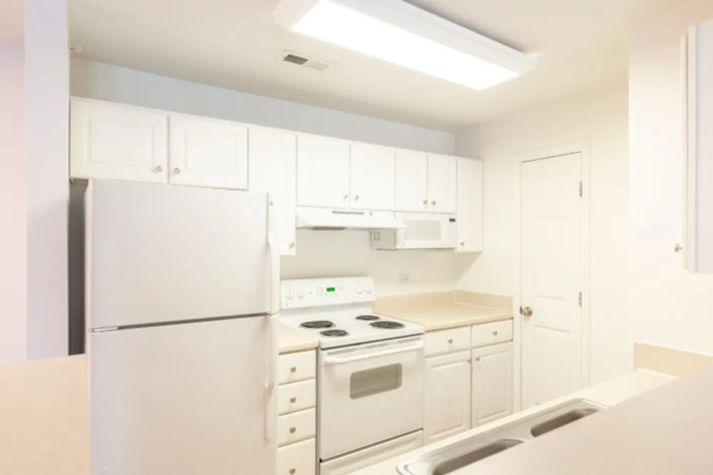 A kitchen with white cabinets, a refrigerator, stove, microwave, and sink.