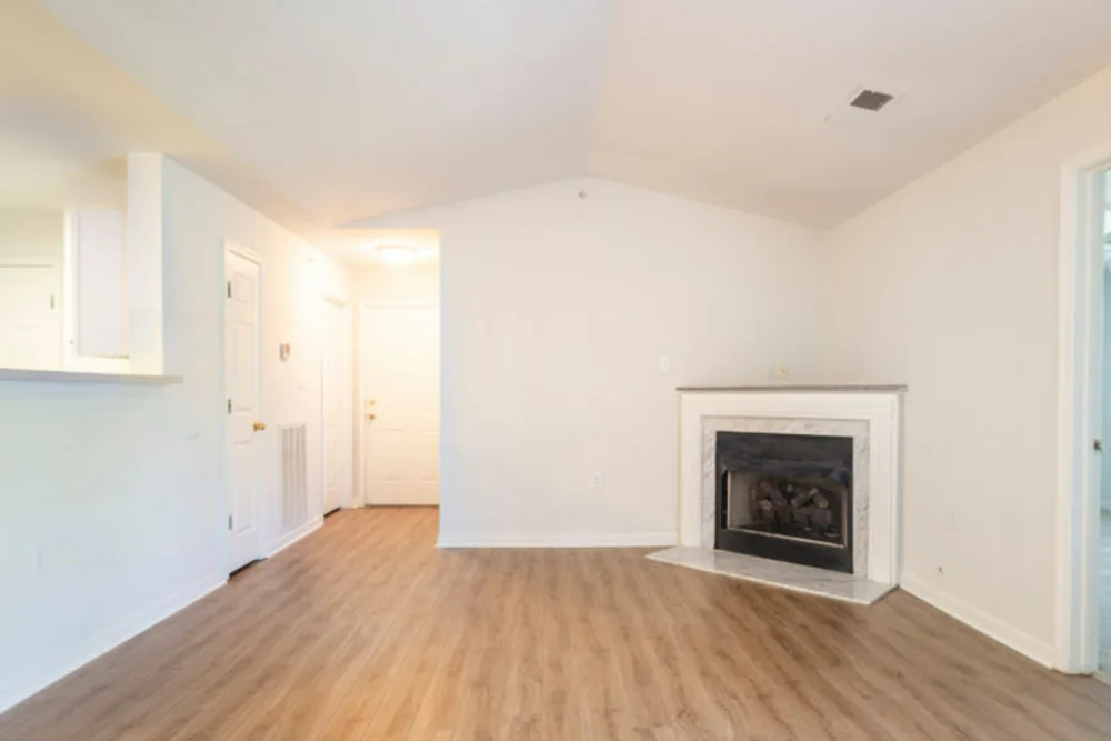 An empty living room with hardwood floors and a fireplace.