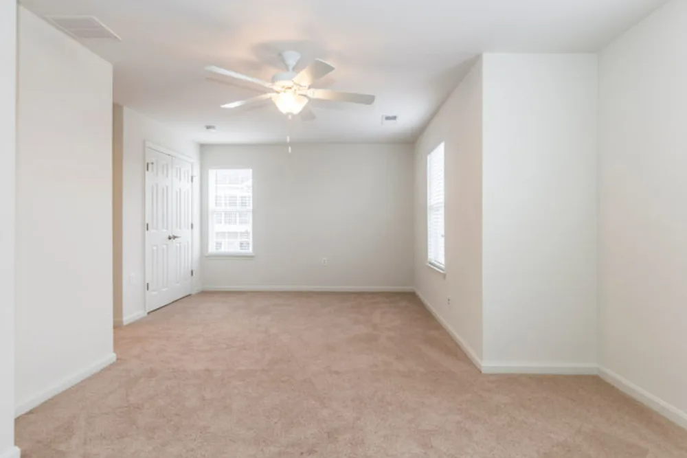 An empty room with a ceiling fan and a window.