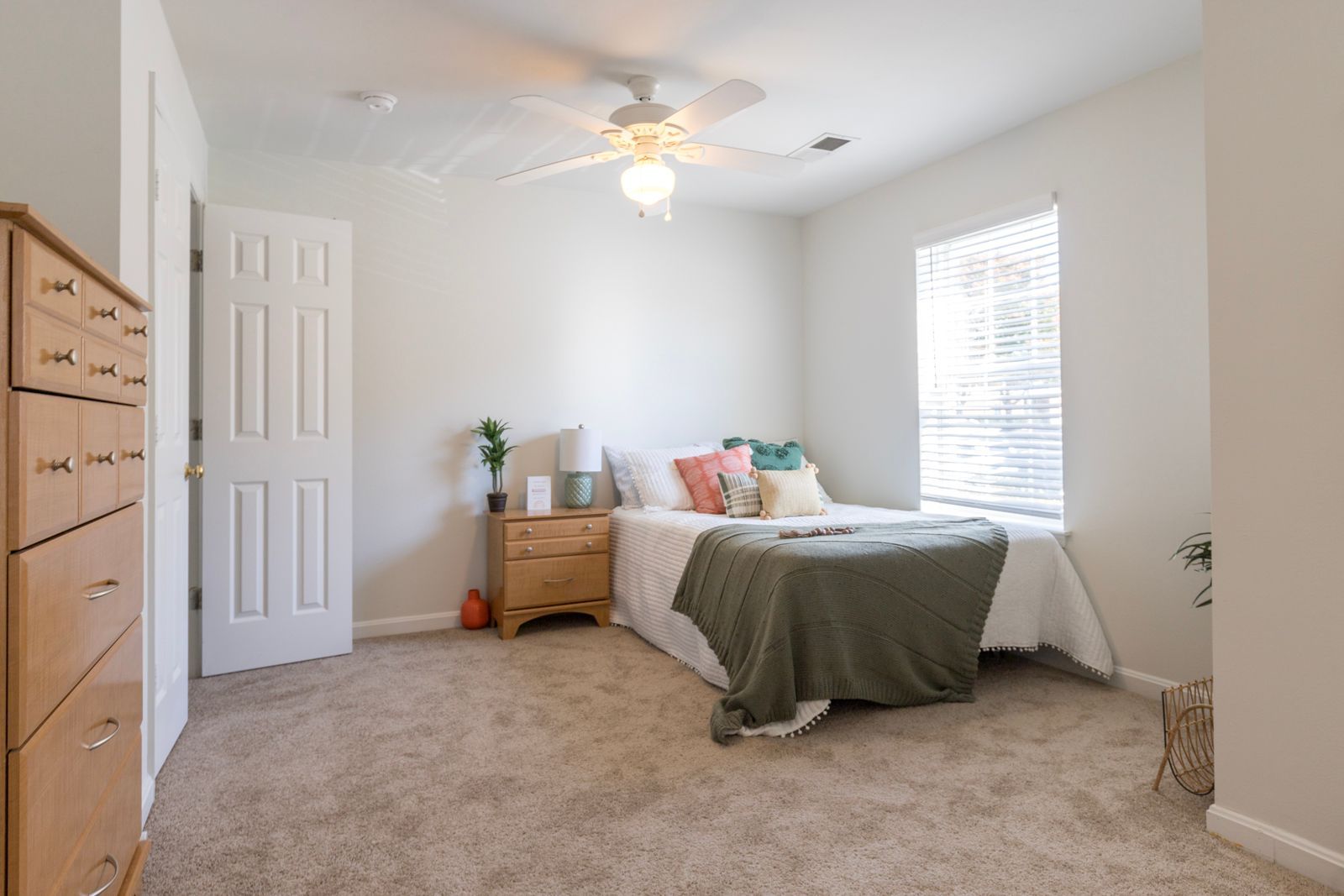 A bedroom with a bed , dresser , nightstand and ceiling fan.