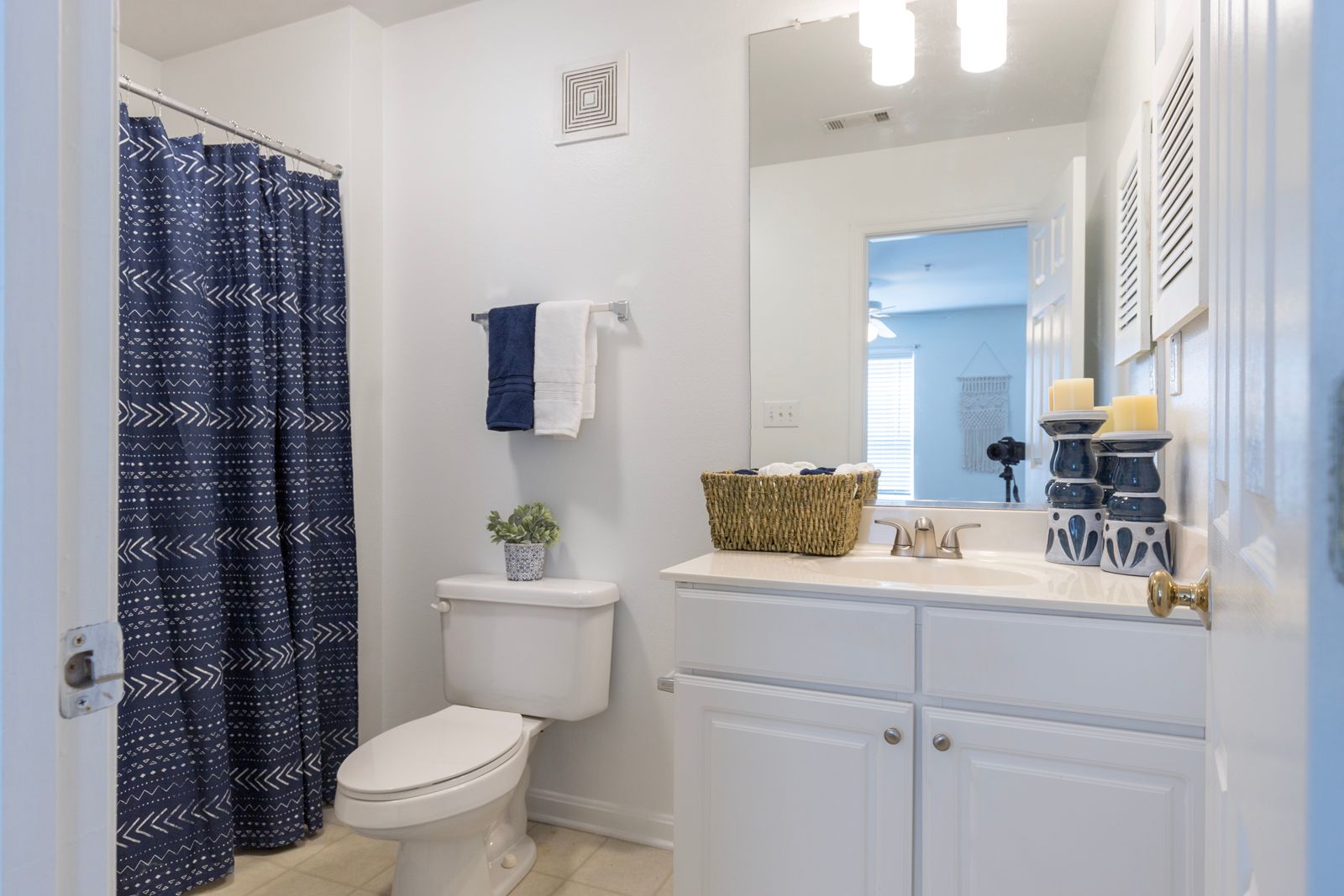 A bathroom with a toilet , sink , mirror and shower curtain.