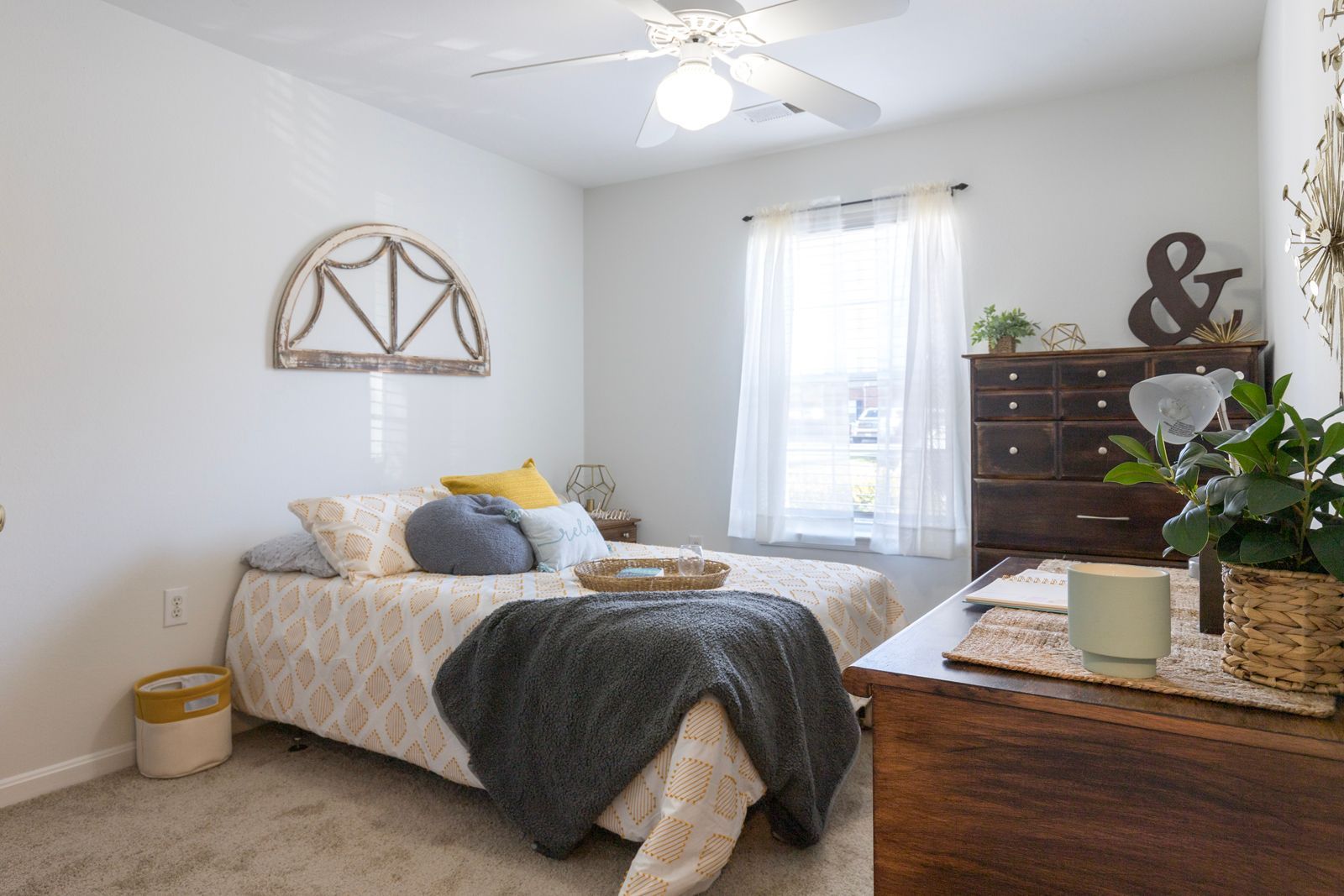 A bedroom with a bed , dresser , nightstand and ceiling fan.