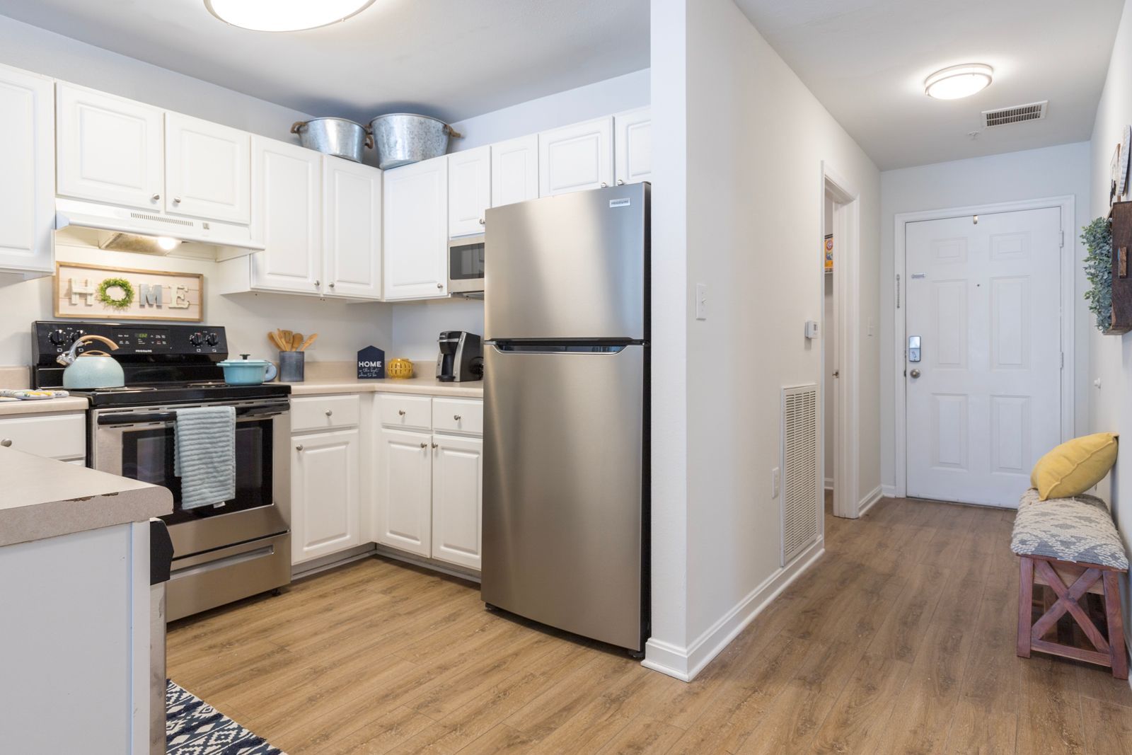 A kitchen with white cabinets , stainless steel appliances and a stainless steel refrigerator.