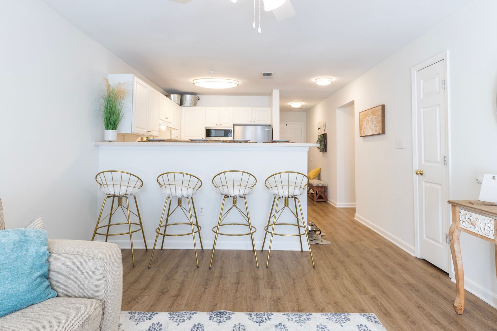 A living room with a couch and stools and a kitchen in the background.