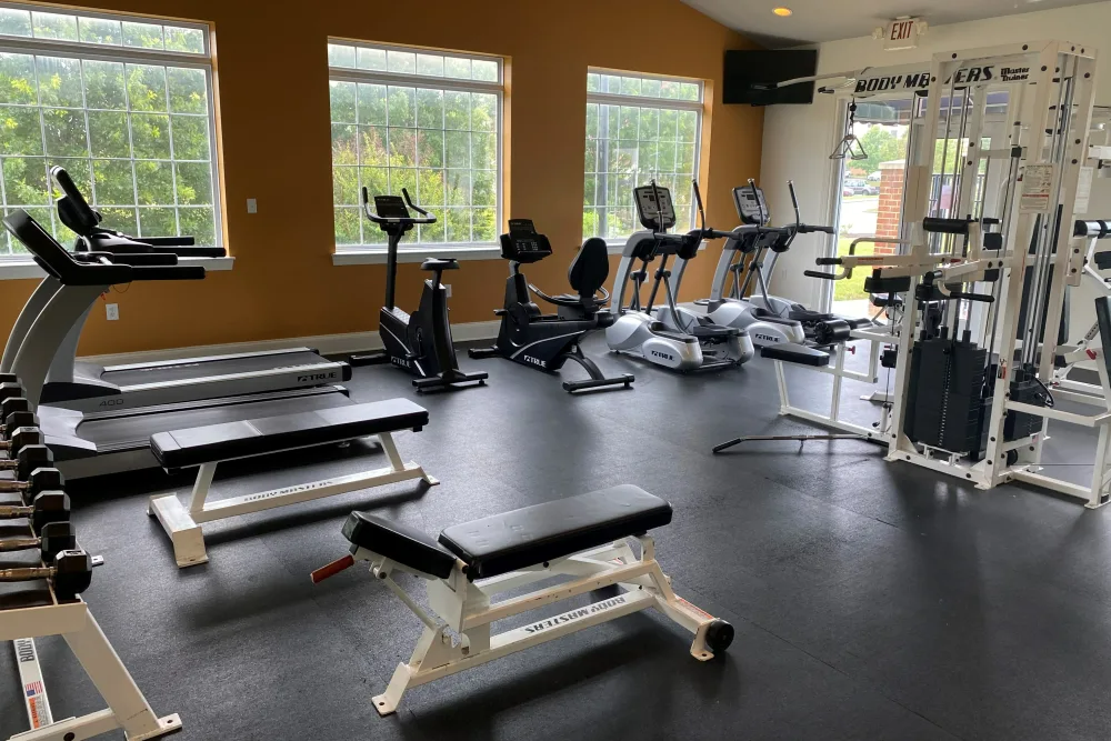 A gym filled with lots of exercise equipment and a bench.