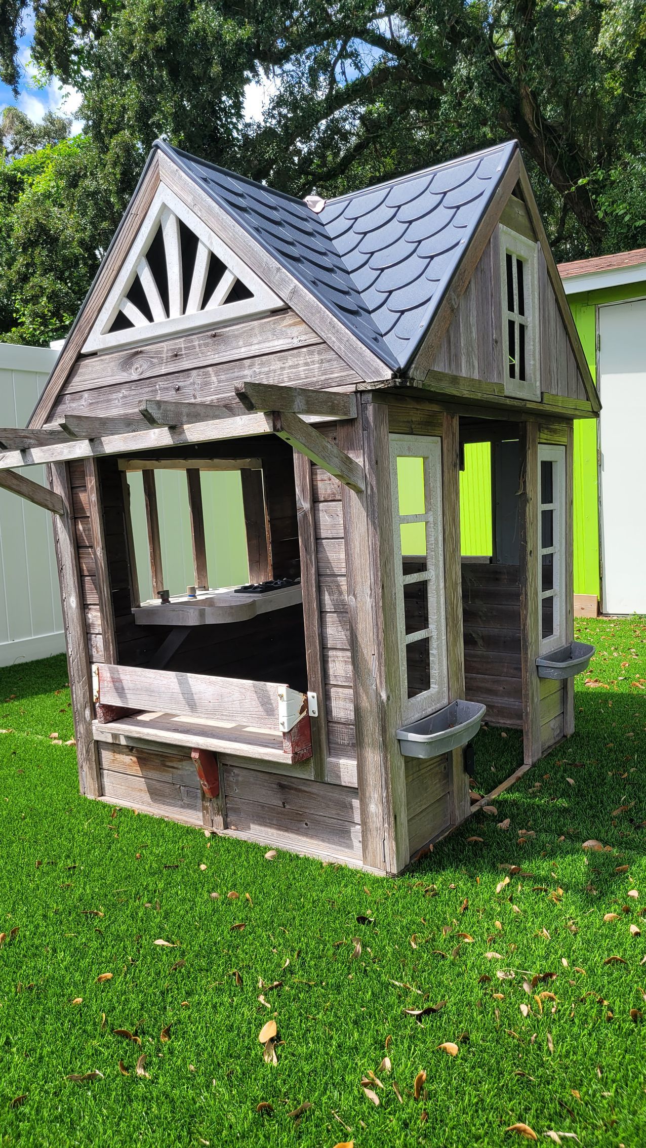 Wooden playhouse on green lawn at Raising Angels.