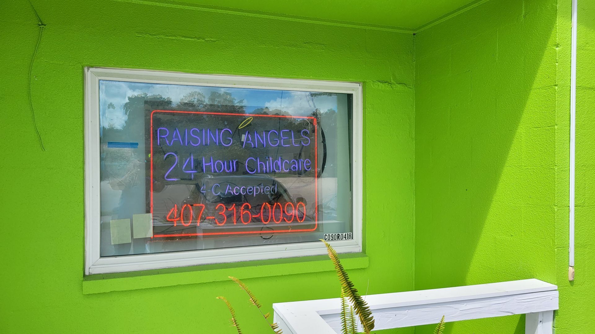 A green building with a neon sign on the window.