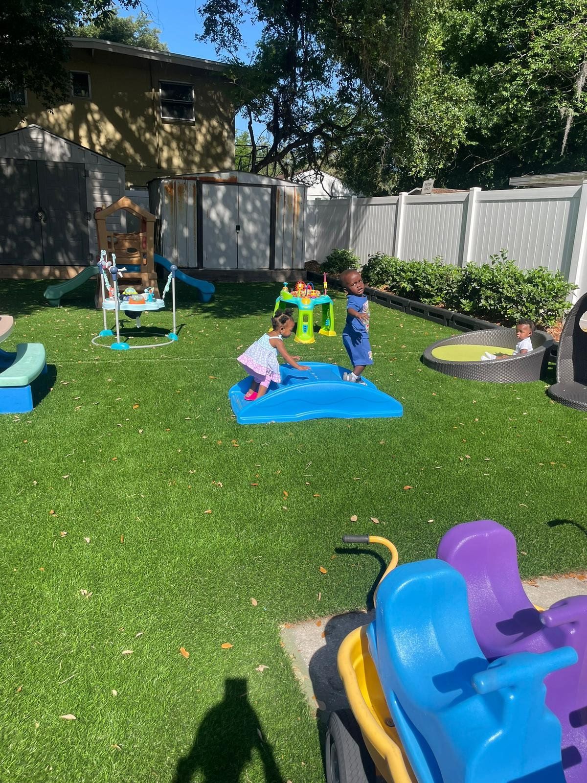 Children climbing on blue play structure at Raising Angels daycare outdoor area.