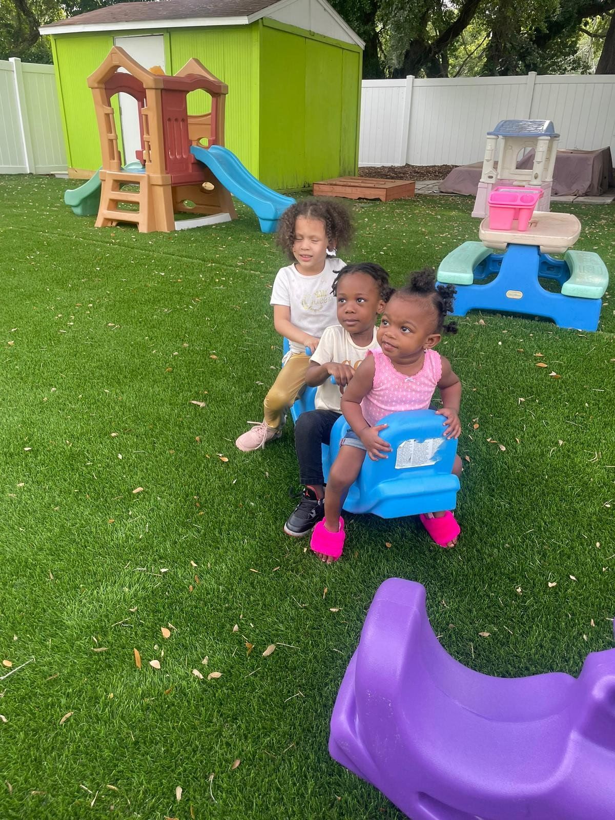 Children riding a seesaw on outdoor turf at Raising Angels Childcare.
