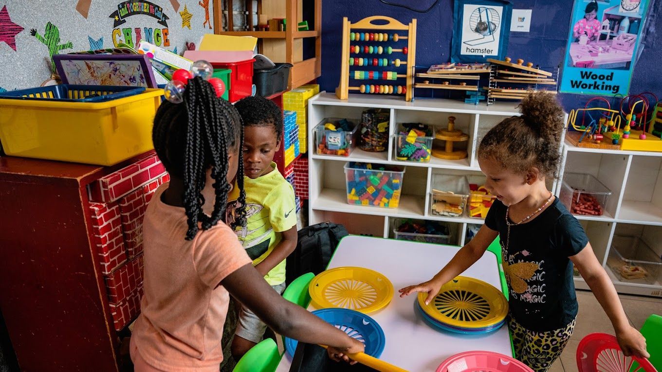 Three children playing in colorful Raising Angels classroom.