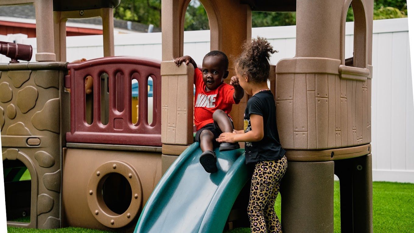 Kids sliding and having fun on daycare playground at Raising Angels.