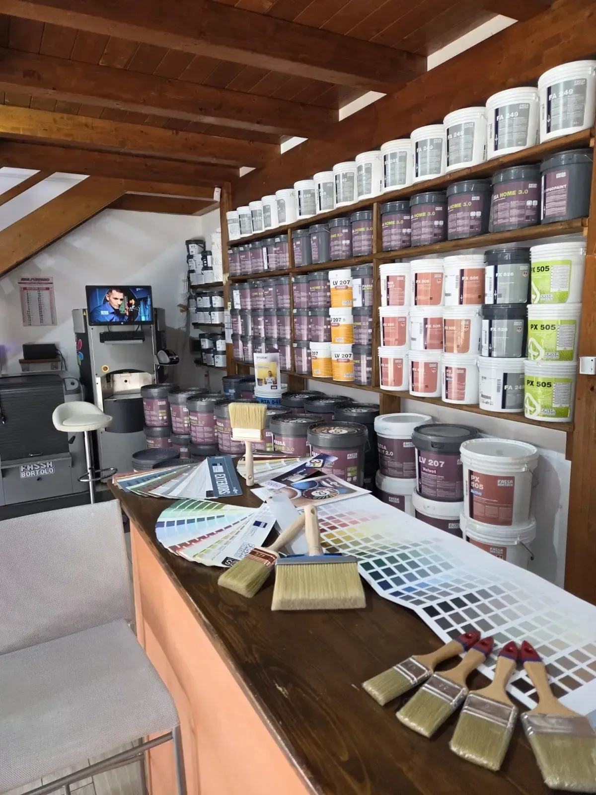 Scaffali pieni di secchi di vernice di vari colori; interno del negozio.