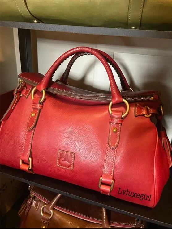 A red leather duffel bag is sitting on a shelf