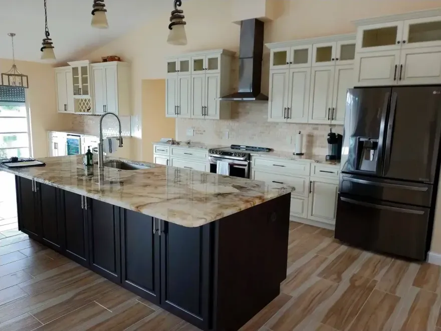 Modern kitchen with island, dark cabinets, granite countertop, stainless steel appliances, and cream-colored upper cabinets.