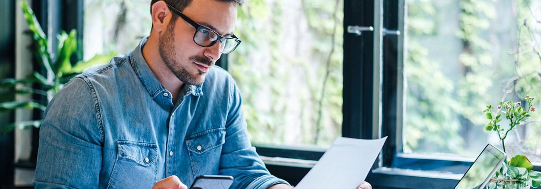 A close up of an open cash register drawer with Australian currency and a hand holding $100 notes as if to be taking a payment from a customer.