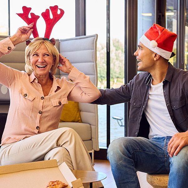 Two people at a staff Christmas party. They're wearing Christmas hats.