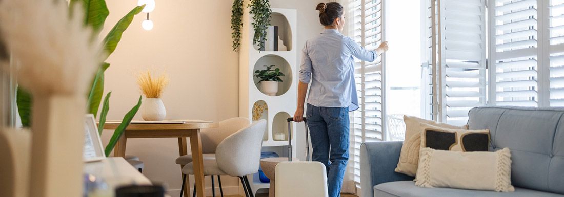 A close up of an open cash register drawer with Australian currency and a hand holding $100 notes as if to be taking a payment from a customer.