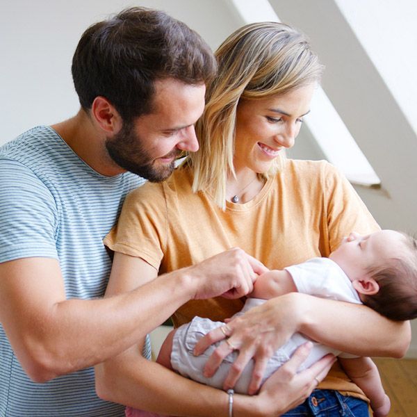 New parents with the Dad holding the baby and the Mum watching on 