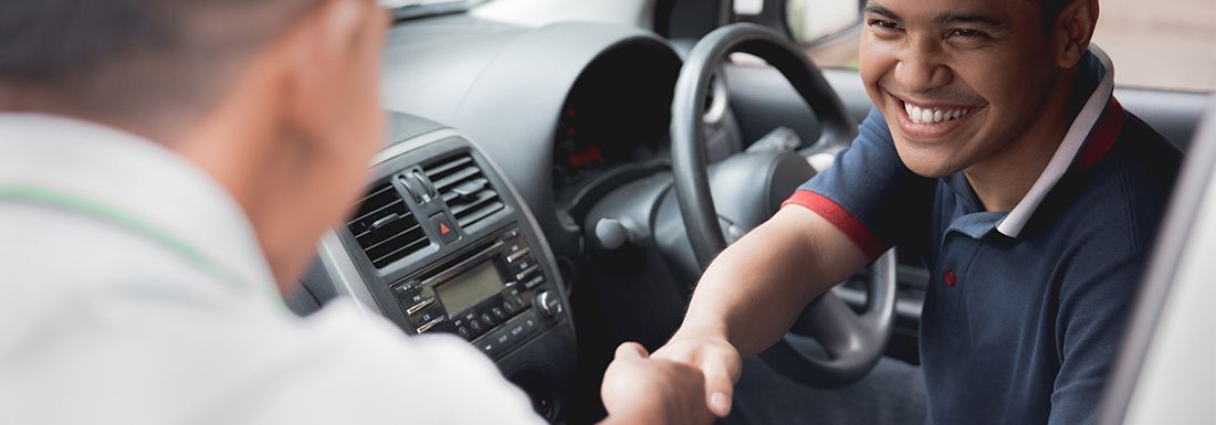 Uber driver sitting in car and shaking the hand of a customer