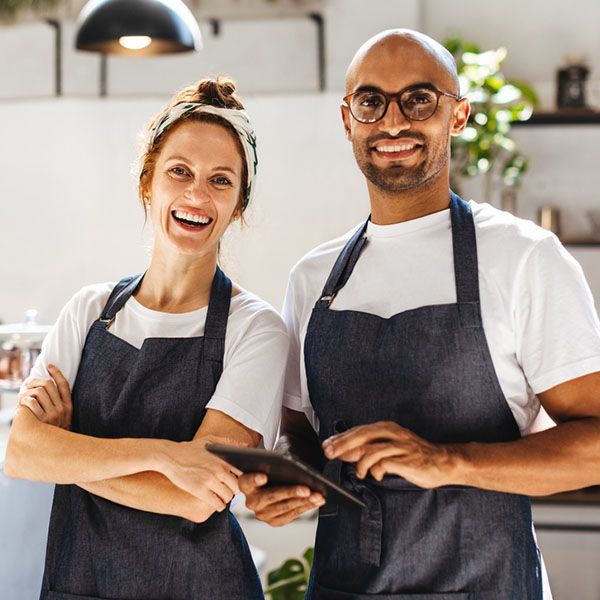 Business owners in their cafe - looking at the camera, smiling.